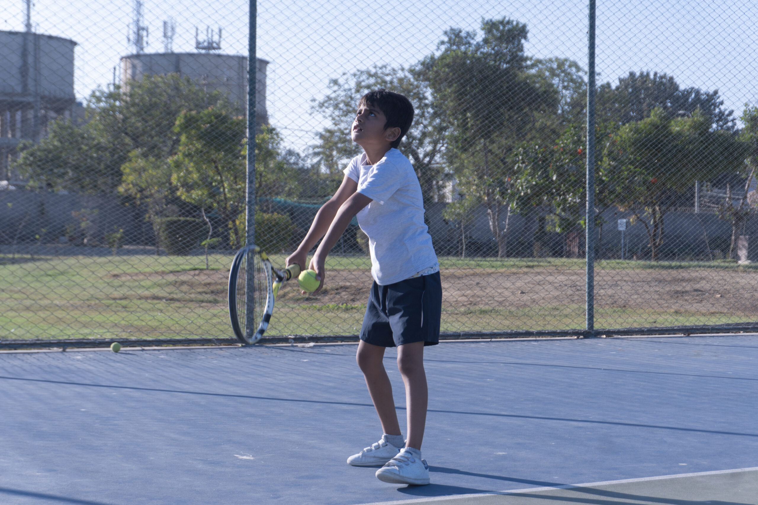 Junior tennis player tossing the ball to serve at Baseline Tennis Academy in DHA, Karachi