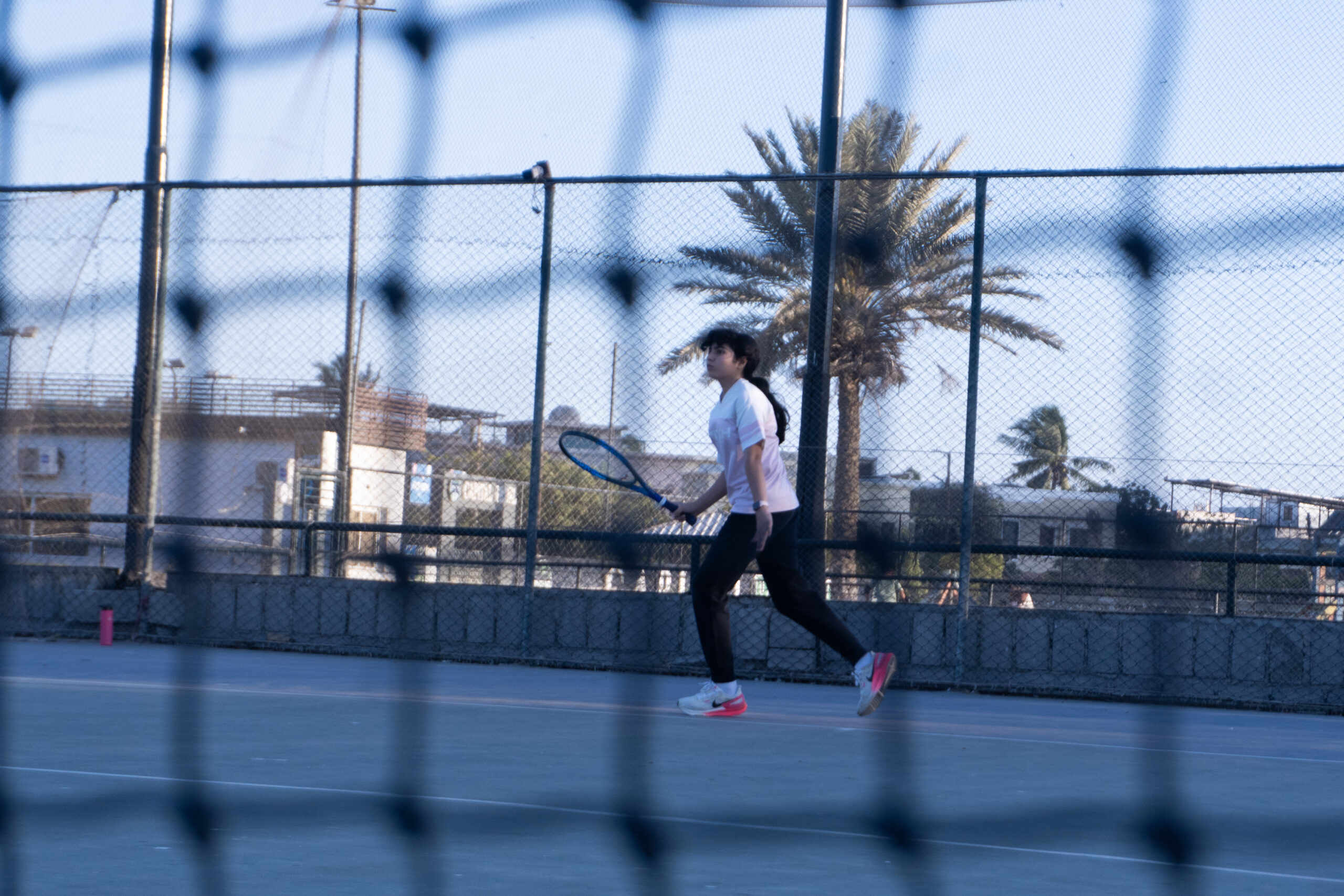 Player rallying on an outdoor hard court at Baseline Tennis Academy in DHA, Karachi