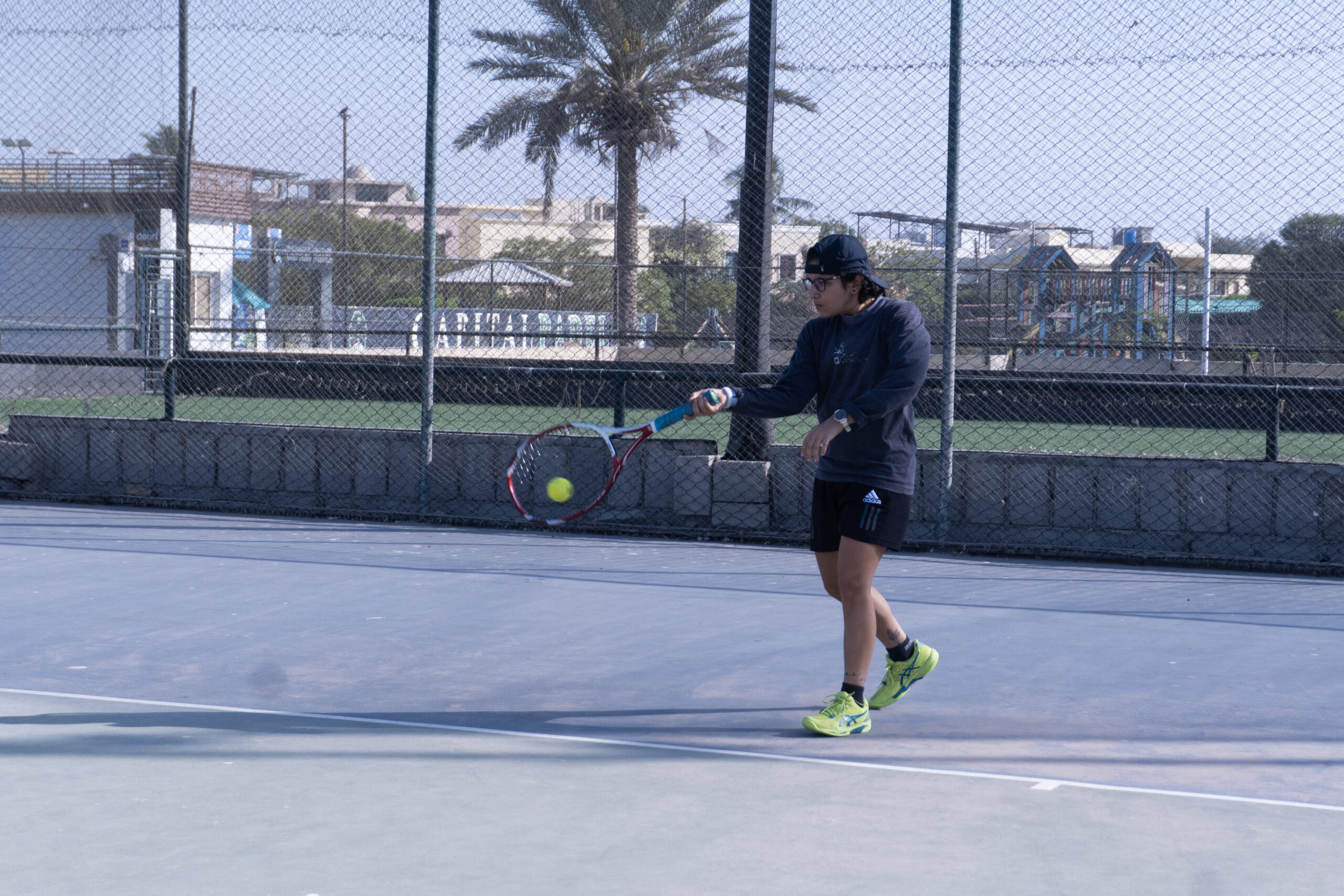Junior player hitting a forehand on an outdoor court during a holiday tennis camp at Baseline Tennis Academy, DHA, Karachi