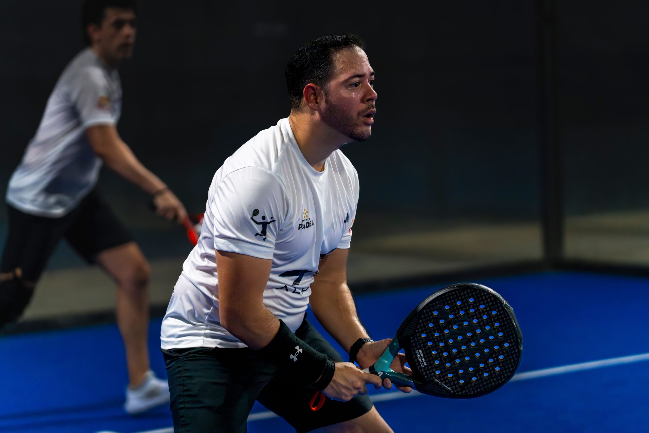 Two padel players rallying on an indoor court, illustrating a first padel session at Baseline Tennis Academy in DHA, Karachi